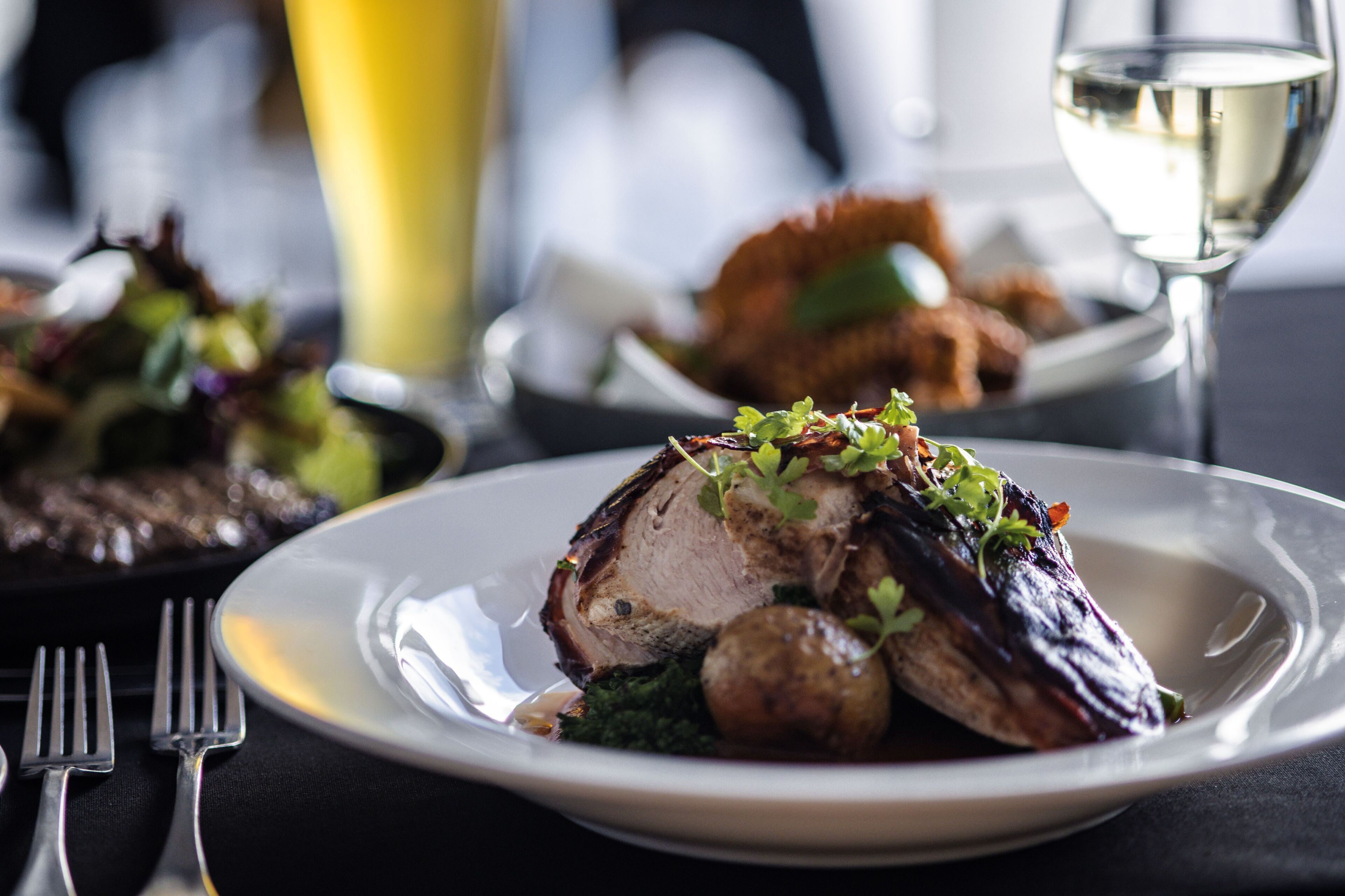 A plate of food with a fork and a glass of white wine.