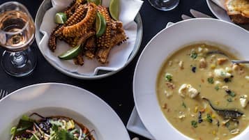 A table with various dishes including a bowl of soup, a plate of corn on the cob, and a salad.
