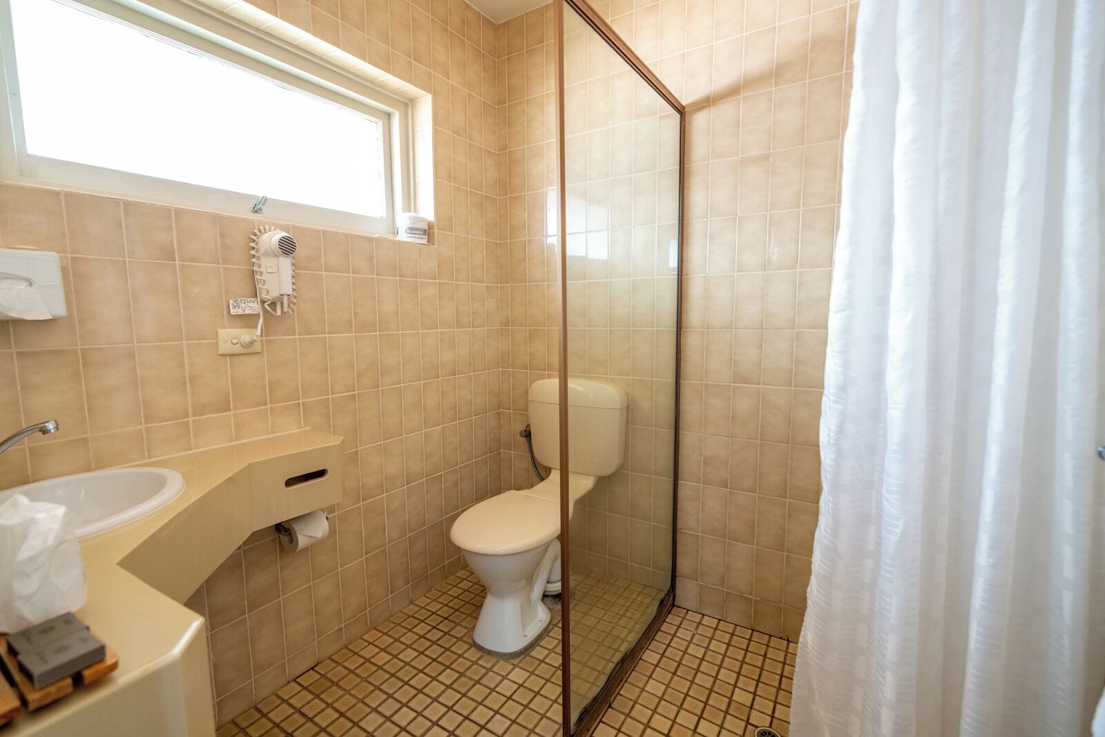 Une salle de bain comprenant des toilettes, un lavabo et un espace douche.