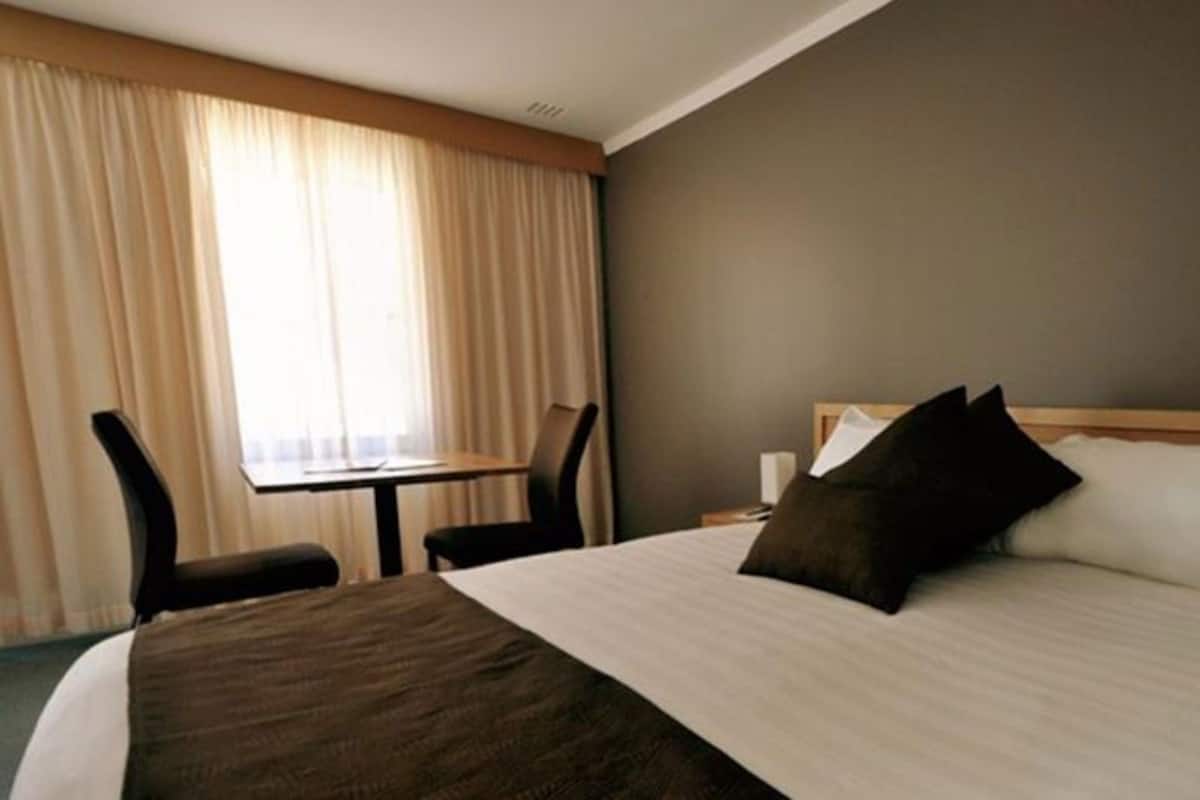 Une chambre d’hôtel avec un lit, un bureau et une chaise.