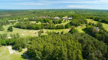 Luchtbeeld van een golfbaan met een clubhuis, omgeven door dichte bossen en open grasvelden.