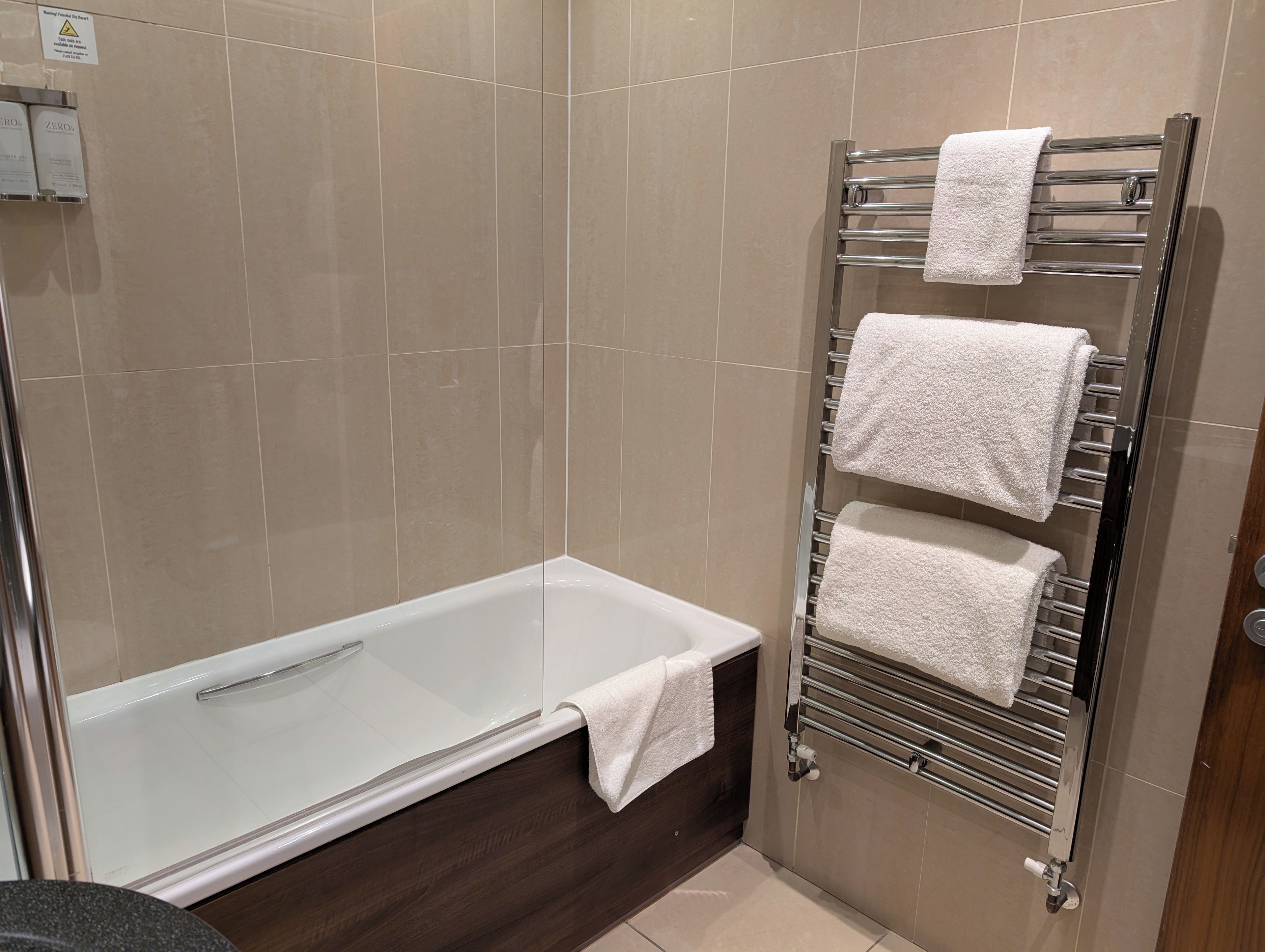 Un baño con una bañera, un perchero con tres toallas y una zona de ducha.