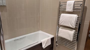 A bathroom with a bathtub, a towel rack with three towels, and a shower area.