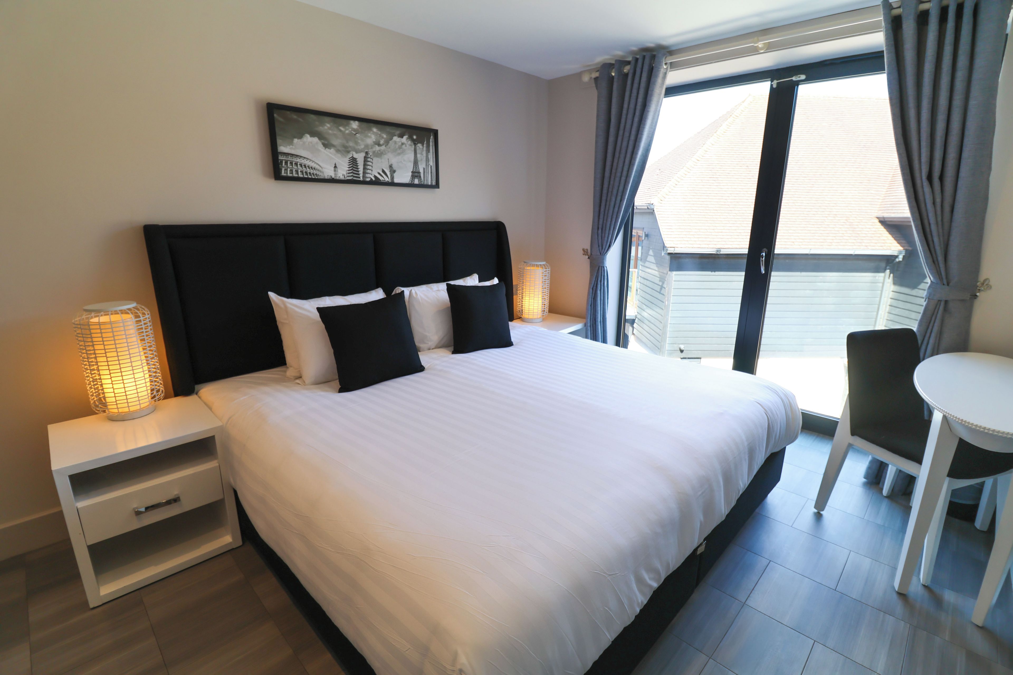 A hotel room with a large bed, bedside tables, a desk, and a chair.