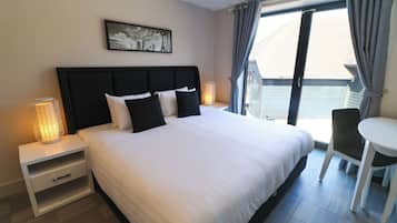 A hotel room with a large bed, bedside tables, a desk, and a chair.