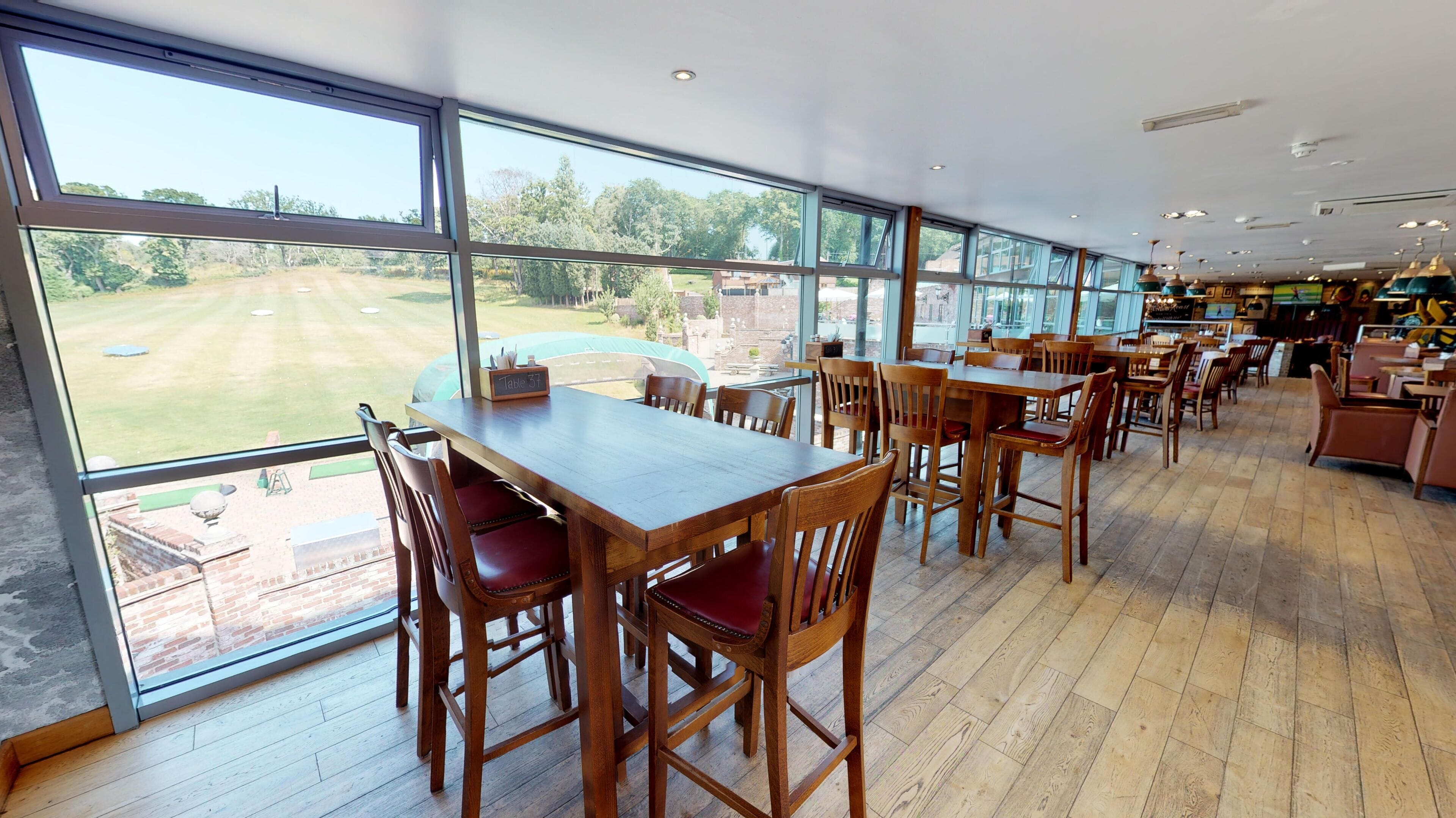A spacious dining area with large windows overlooking a golf course.