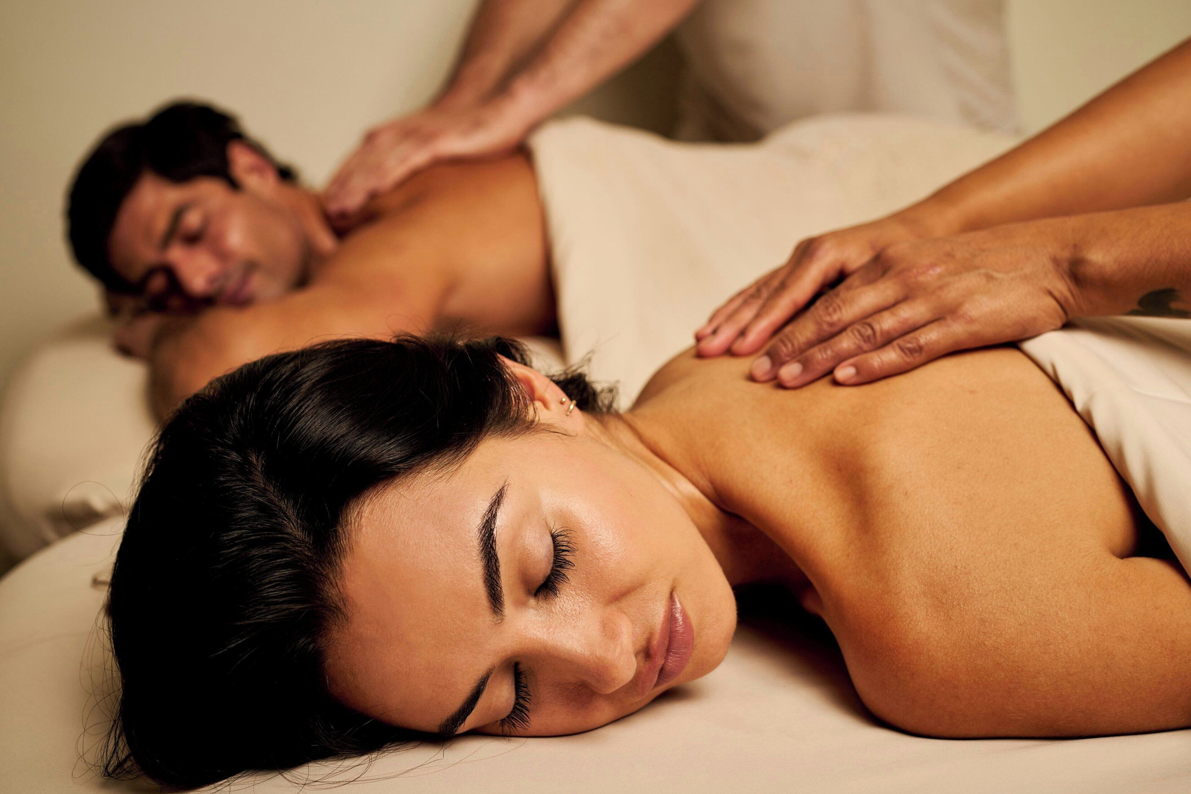 A massage therapy session in a spa setting with a focus on the therapist's hands on a client's back.