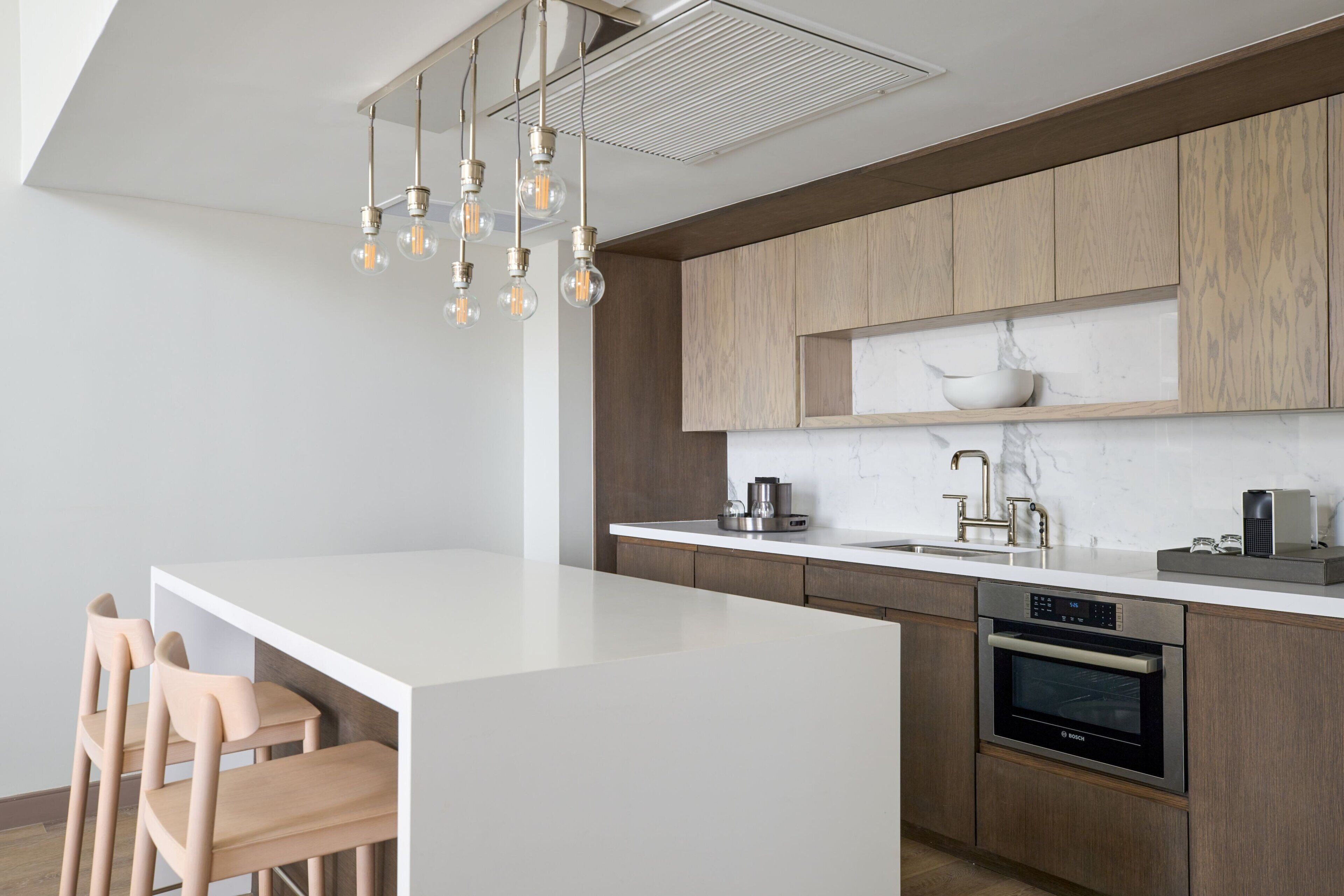 Una cocina moderna con una isla blanca, armarios de madera y un horno empotrado.