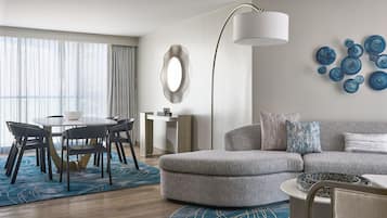 Una sala de estar moderna con un sofá gris, una mesa redonda de centro y una zona de comedor con mesa y sillas.
