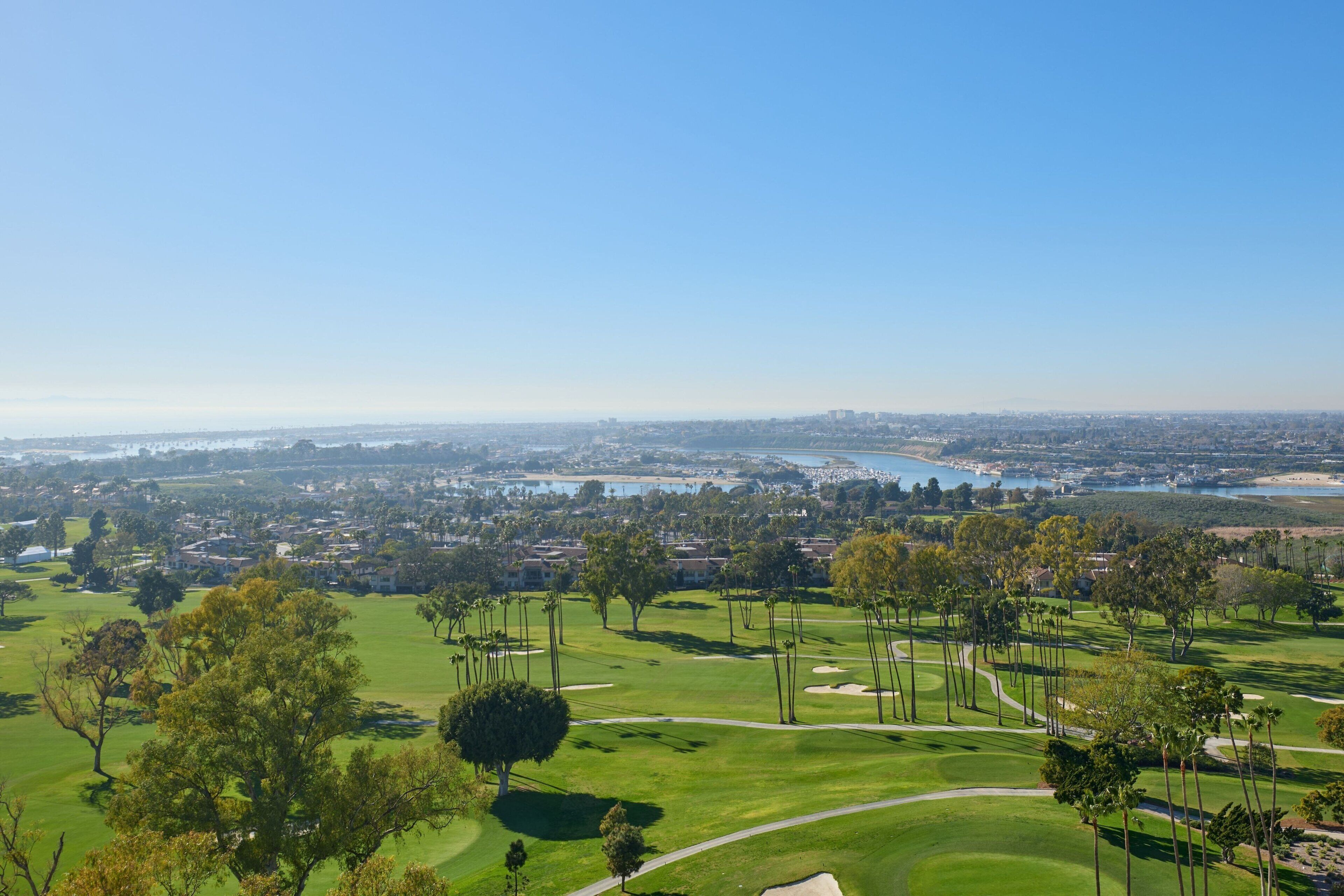 A golf course with a view of a city and a body of water in the distance.