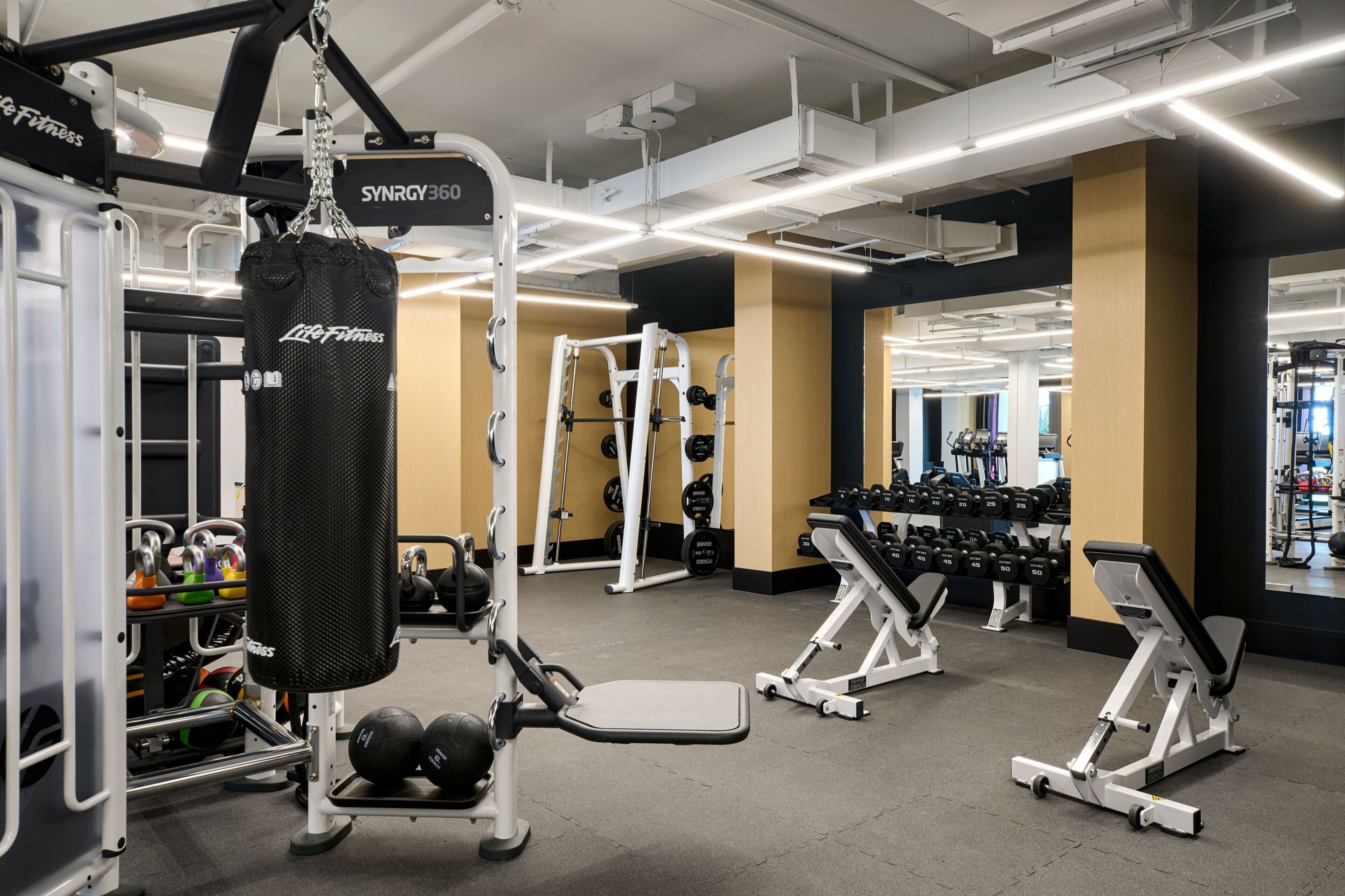 A gym with various exercise equipment, including a punching bag, weight machines, and dumbbells.
