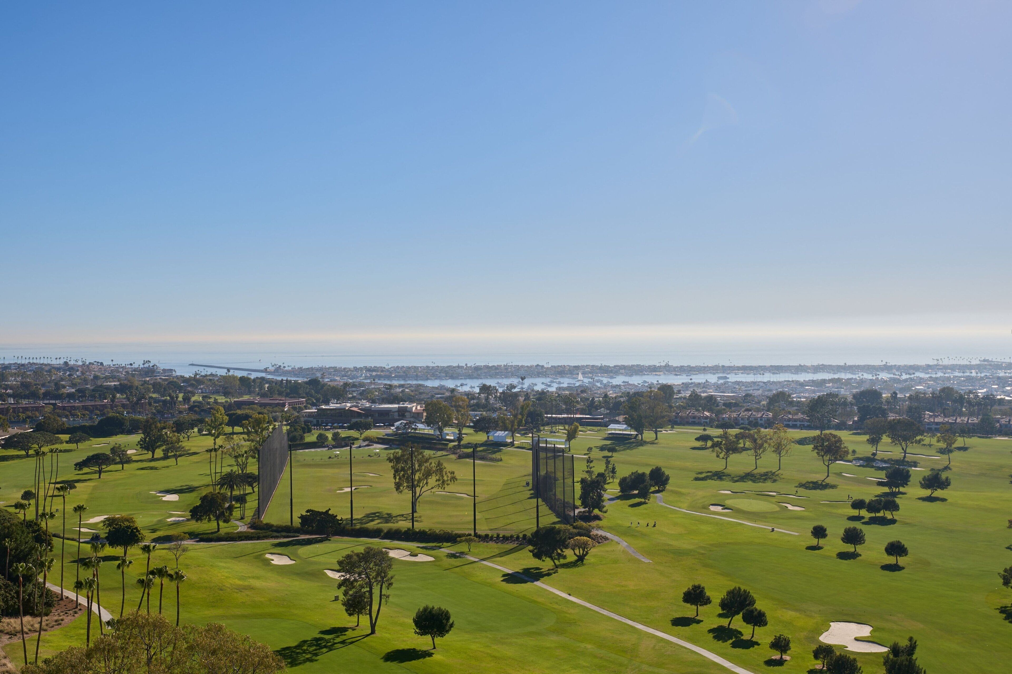 A golf course with multiple holes, sand bunkers, and trees.