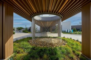 Una estructura arquitectónica moderna de diseño circular, rodeada por un jardín ajardinado con rocas y césped.