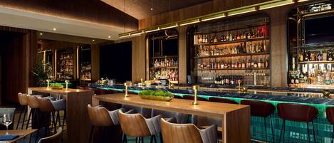A bar area with wooden bar counters, stools, and shelves of bottles.