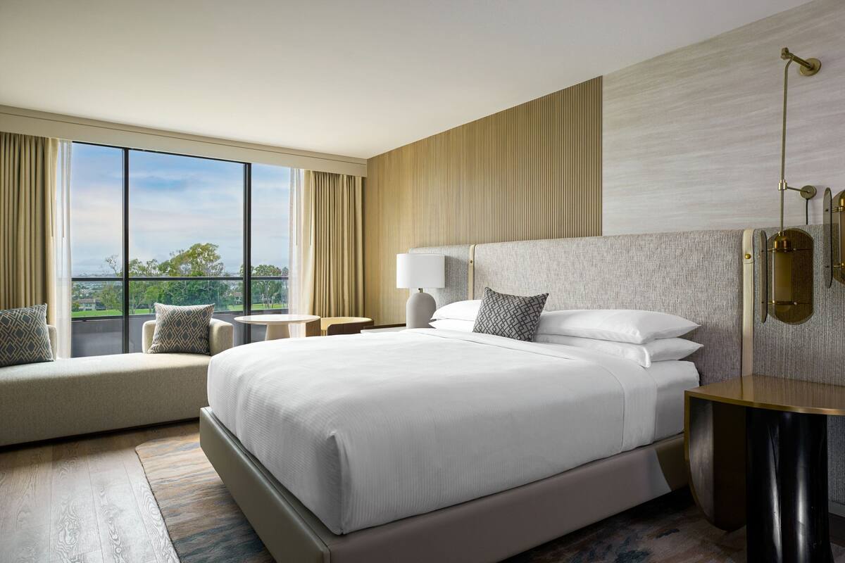 Una habitación de hotel moderna con una cama grande, un espacio de descanso junto a la ventana y vistas al exterior.