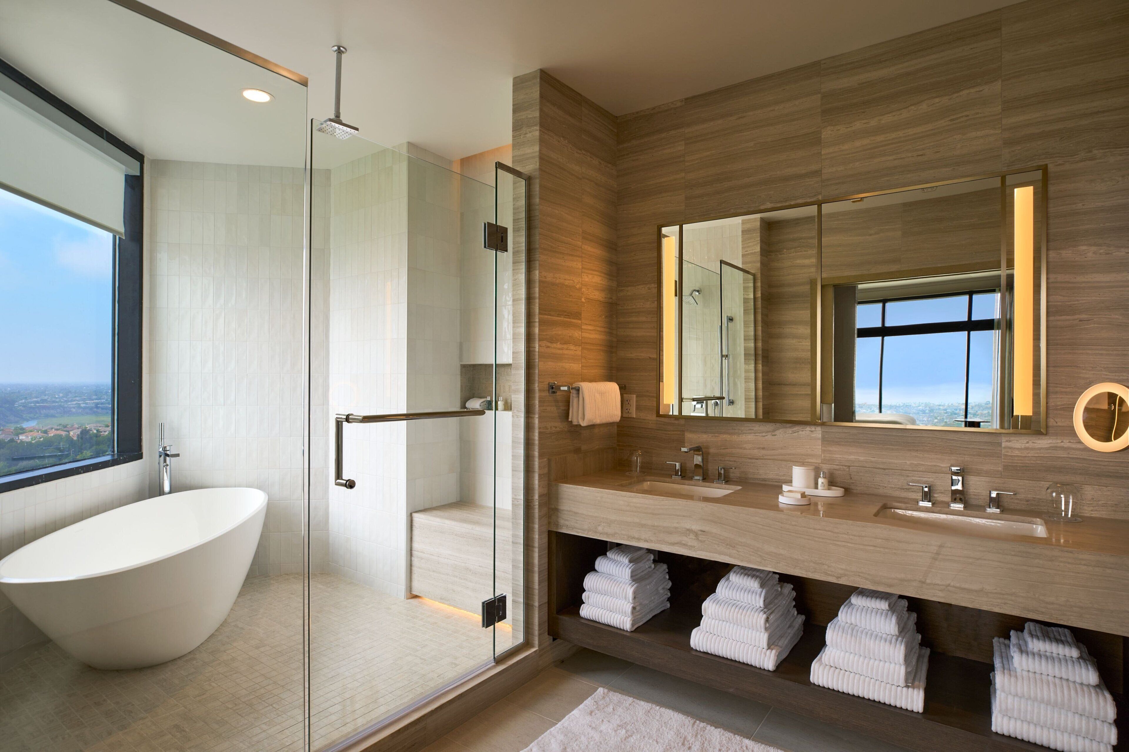 Un baño moderno con una bañera independiente, ducha con mampara de vidrio y un tocador con un espejo grande.
