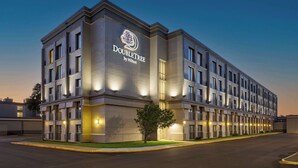 Un moderno edificio de hotel con un logotipo destacado, varios balcones y una fachada bien iluminada.