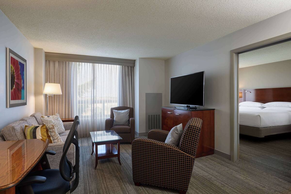 Une chambre d’hôtel équipée d’un canapé, d’un fauteuil, d’une table à manger, d’une télévision et d’un lit.