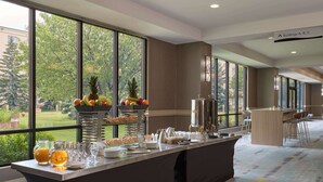 Un comedor de hotel con servicio de buffet, amplias ventanas y vistas al exterior.