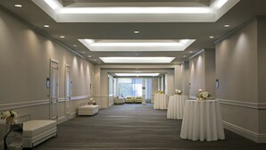 A hotel corridor with a long, carpeted hallway, recessed lighting, and a seating area at the end.
