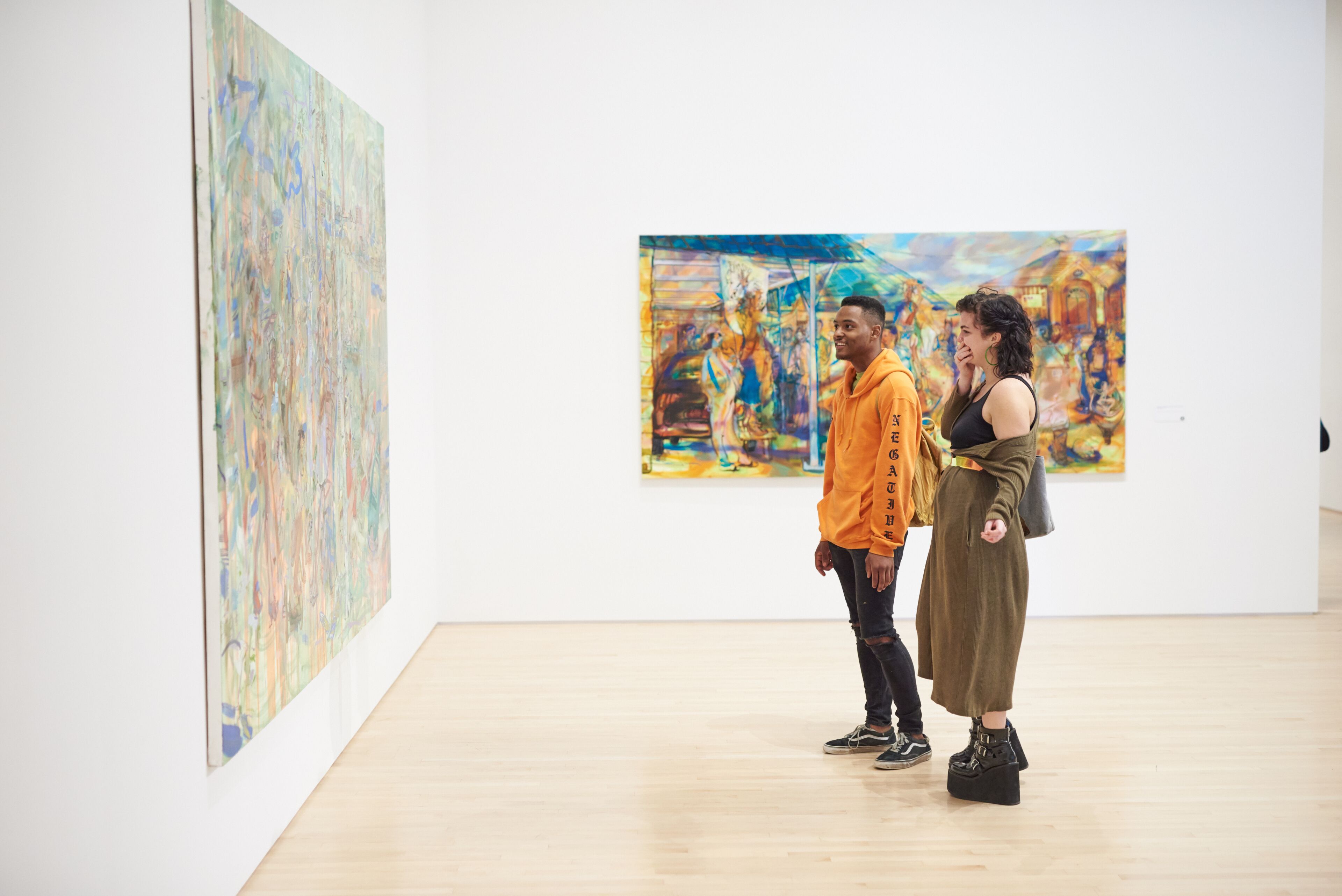 An art gallery with two people observing paintings.