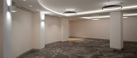 A spacious, modern room with a unique patterned carpet, recessed lighting, and a circular ceiling feature.