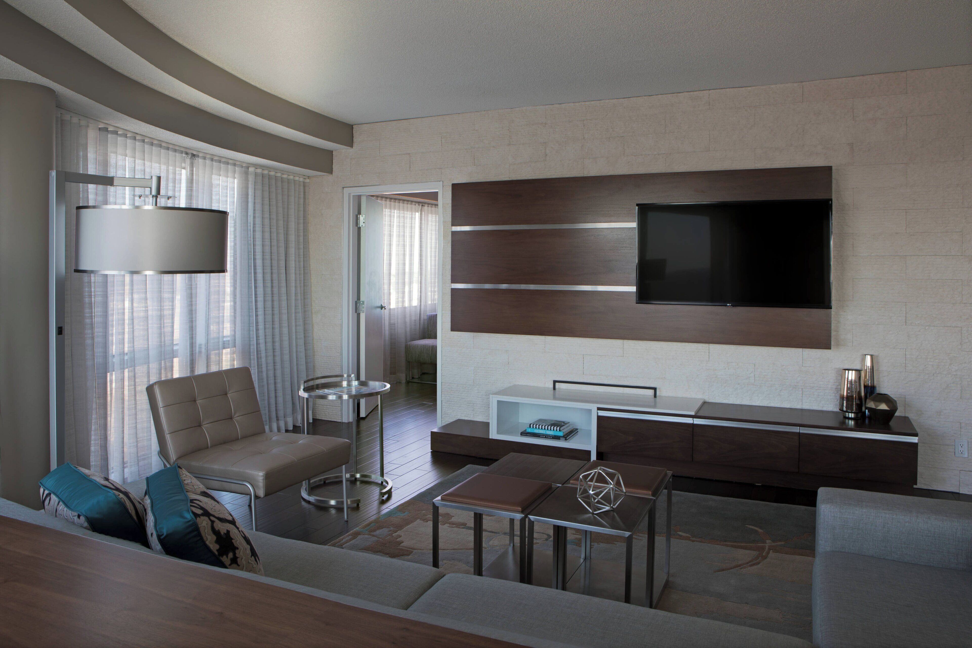 Una sala de estar moderna con un televisor de pantalla plana montado en la pared, un sofá, una mesa de centro y una mesita auxiliar.