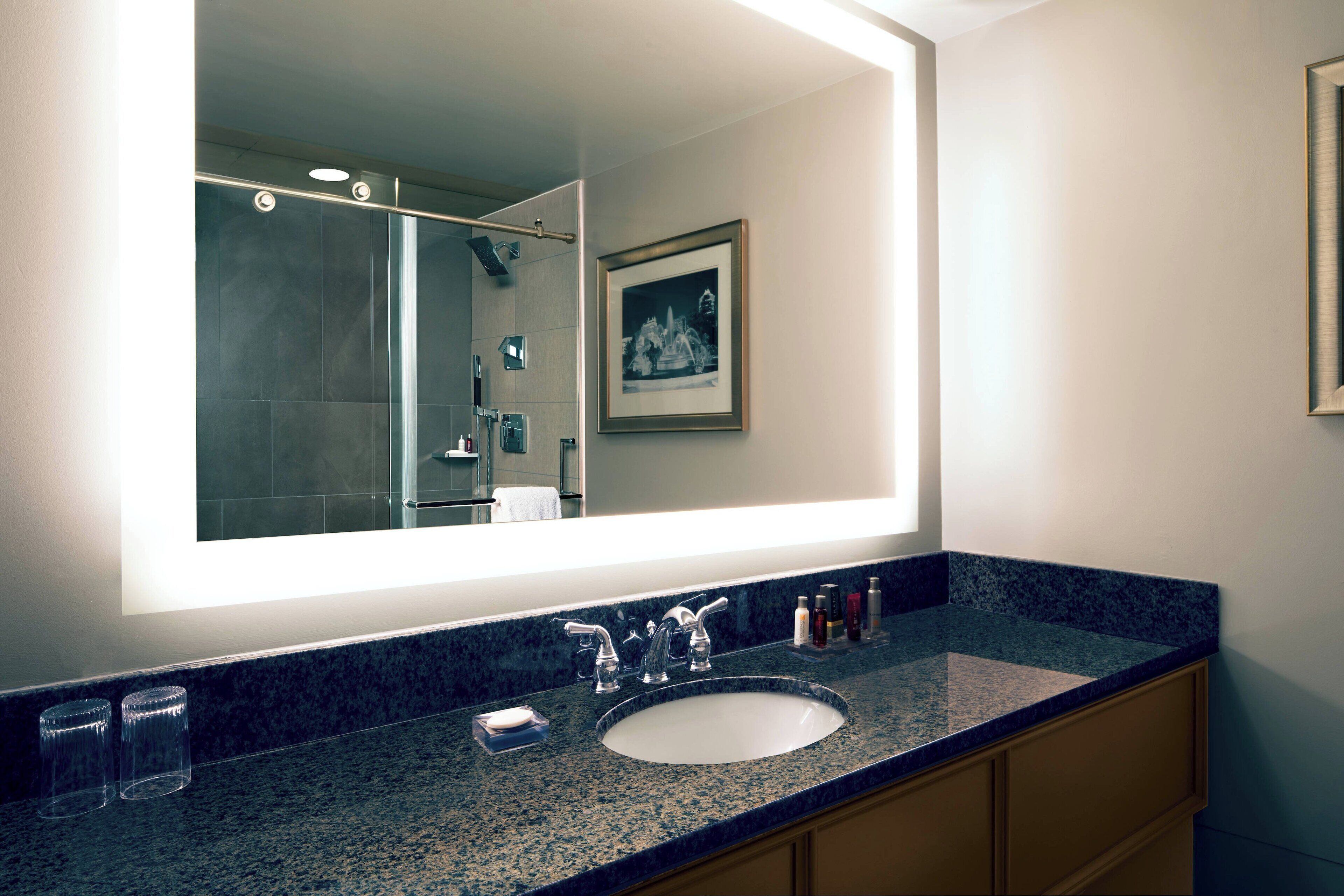 Un baño con un espejo grande, un lavabo y un cuadro en la pared.