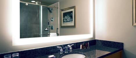 Un baño con un espejo grande, un lavabo y un cuadro en la pared.