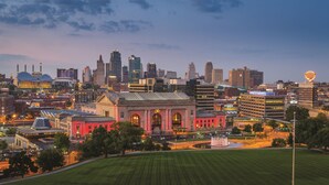 A cityscape with a prominent historic building in the foreground, surrounded by modern skyscrapers.