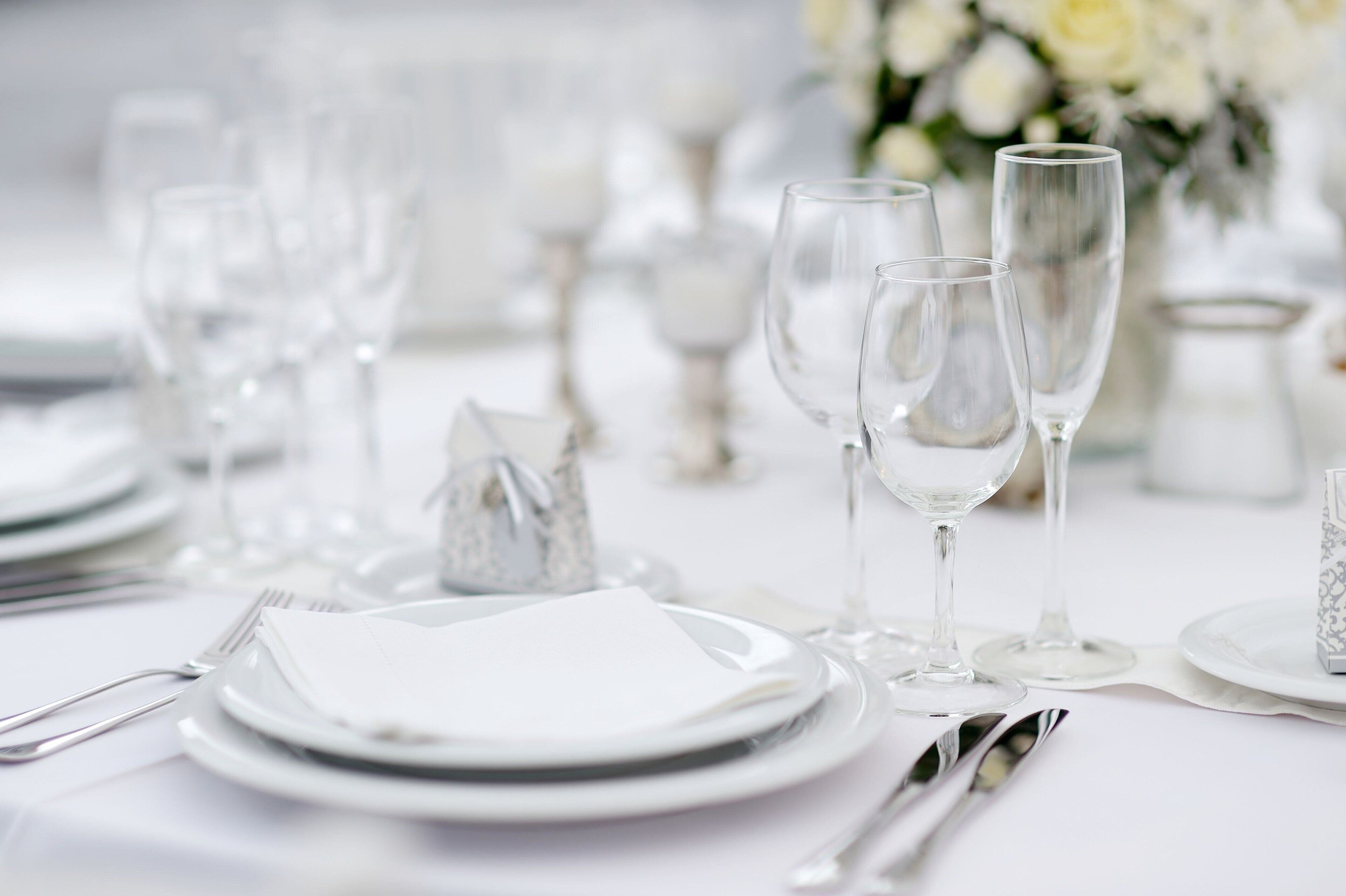 A table set for a formal event with clear glassware, plates, and silverware.