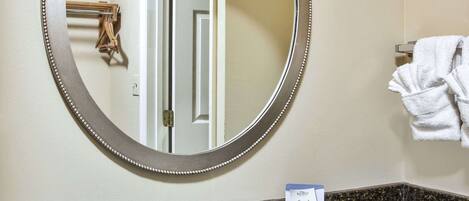 A bathroom with a round mirror, a sink, and a towel rack.