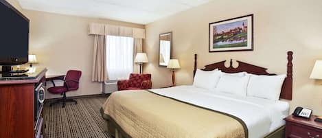 Habitación de hotel con una cama grande, un escritorio con ordenador, una silla, un televisor y un cuadro en la pared.