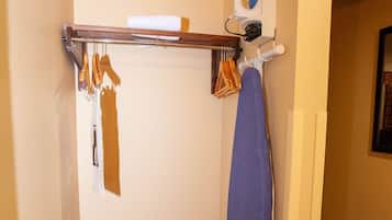A small room with a wooden rack, a blue towel, and a wall-mounted ironing board.