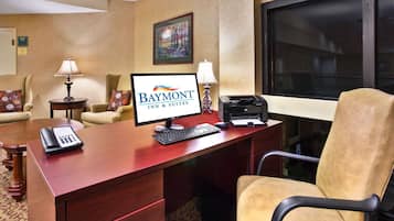 A hotel room with a desk, computer, printer, and two chairs.