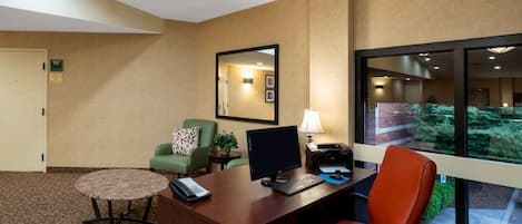Habitación de hotel con escritorio, computadora, silla, mesita y espejo.