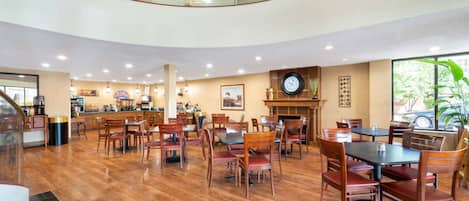A spacious dining area with wooden flooring and multiple tables and chairs.