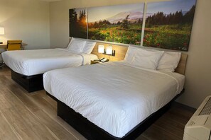 A hotel room with two beds, a nightstand with a lamp, and a painting of a landscape on the wall. - Days Inn by Wyndham Reno (Reno)