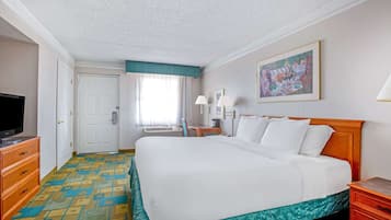 A hotel room with a large bed, a television, a desk, and a painting on the wall.