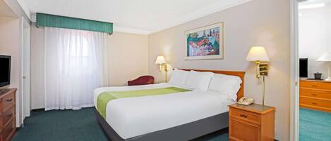 A hotel room with a bed, two bedside tables, a TV, a desk, and a chair.