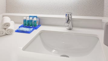 Un lavabo de salle de bain avec des articles de toilette et des serviettes.