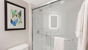 A modern bathroom with a glass shower enclosure, a white toilet, and a framed abstract artwork on the wall. - Holiday Inn Express West Los Angeles by IHG (Los Angeles)