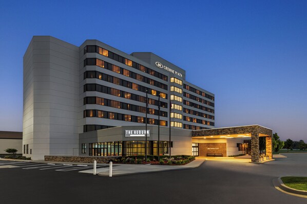 Un hotel de varios pisos con diseño moderno, que cuenta con una entrada destacada con un área techada y el letrero de 'The Auburn'.