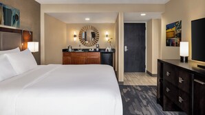 A hotel room with a large bed, a wooden dresser, a mirror, and a television.