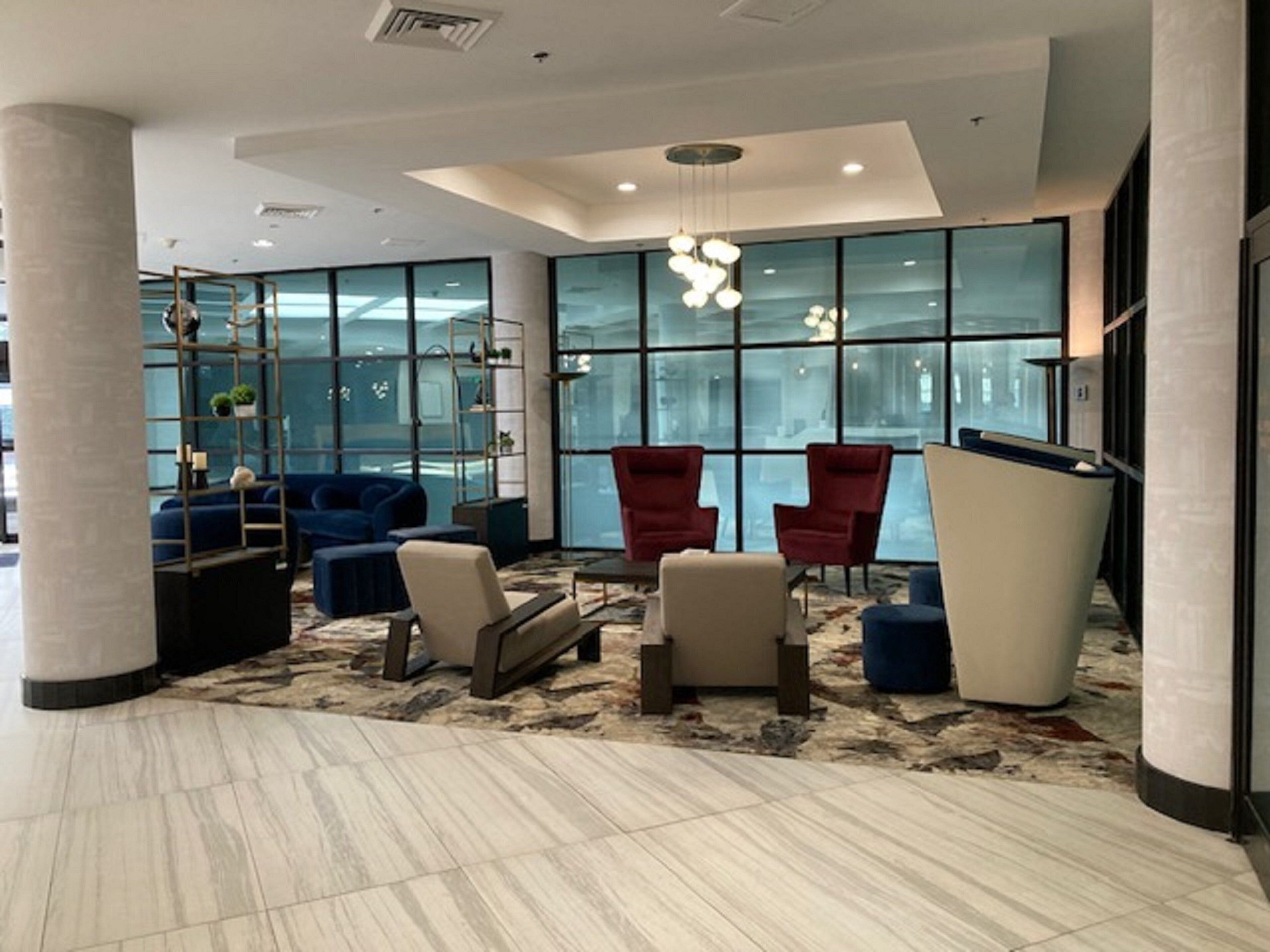 A modern lobby with a seating area, large windows, and a decorative light fixture.