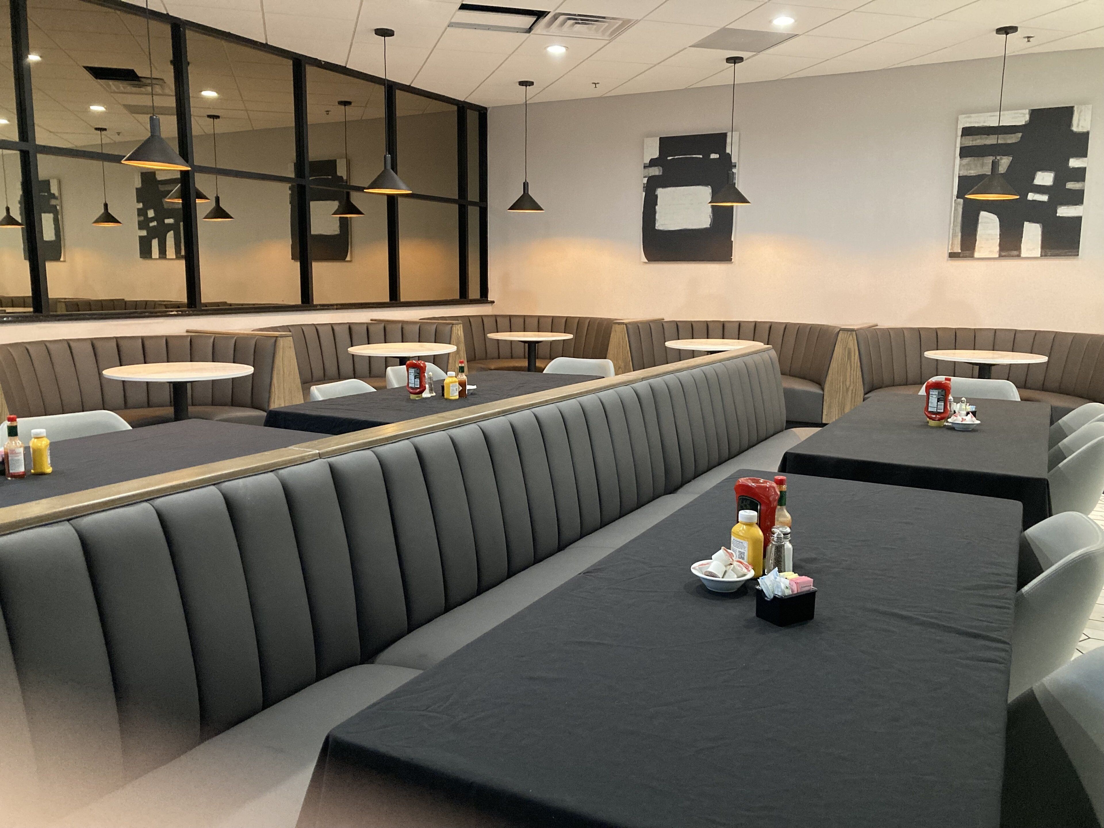A modern restaurant with booth seating and round tables.