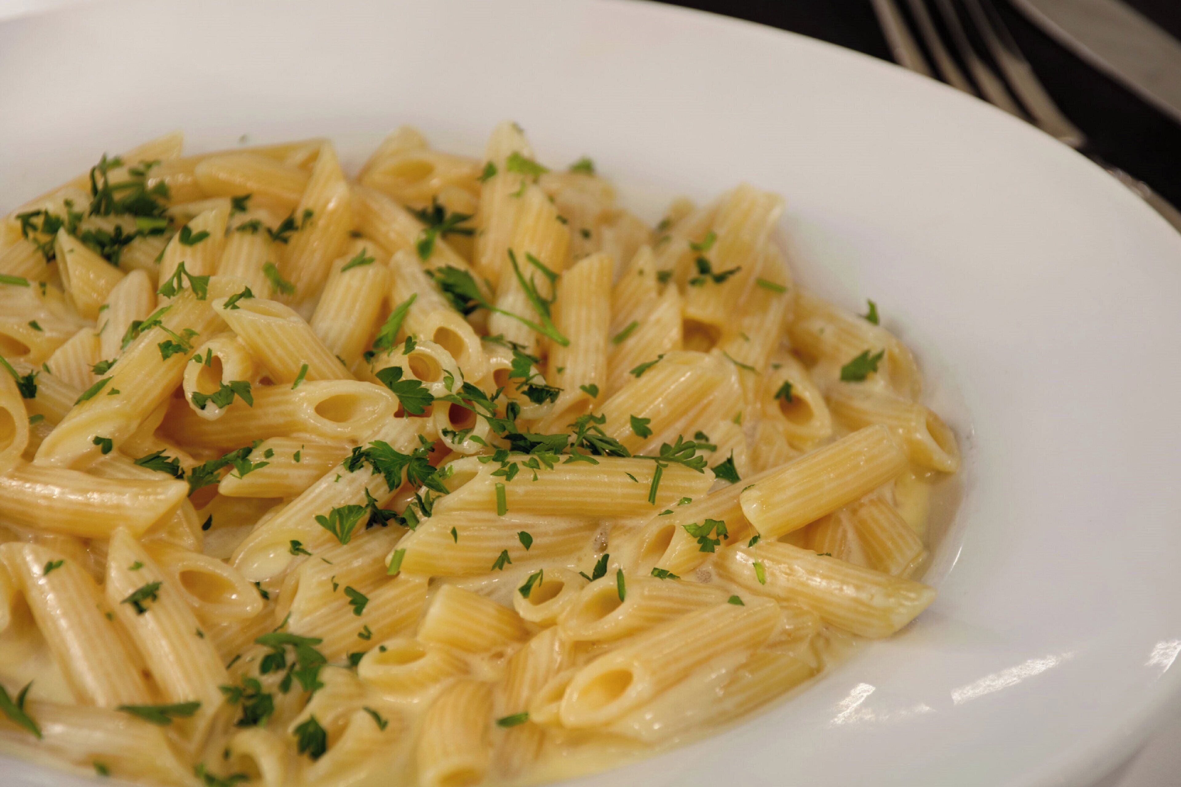 A plate of pasta with a creamy sauce and garnished with chopped herbs.