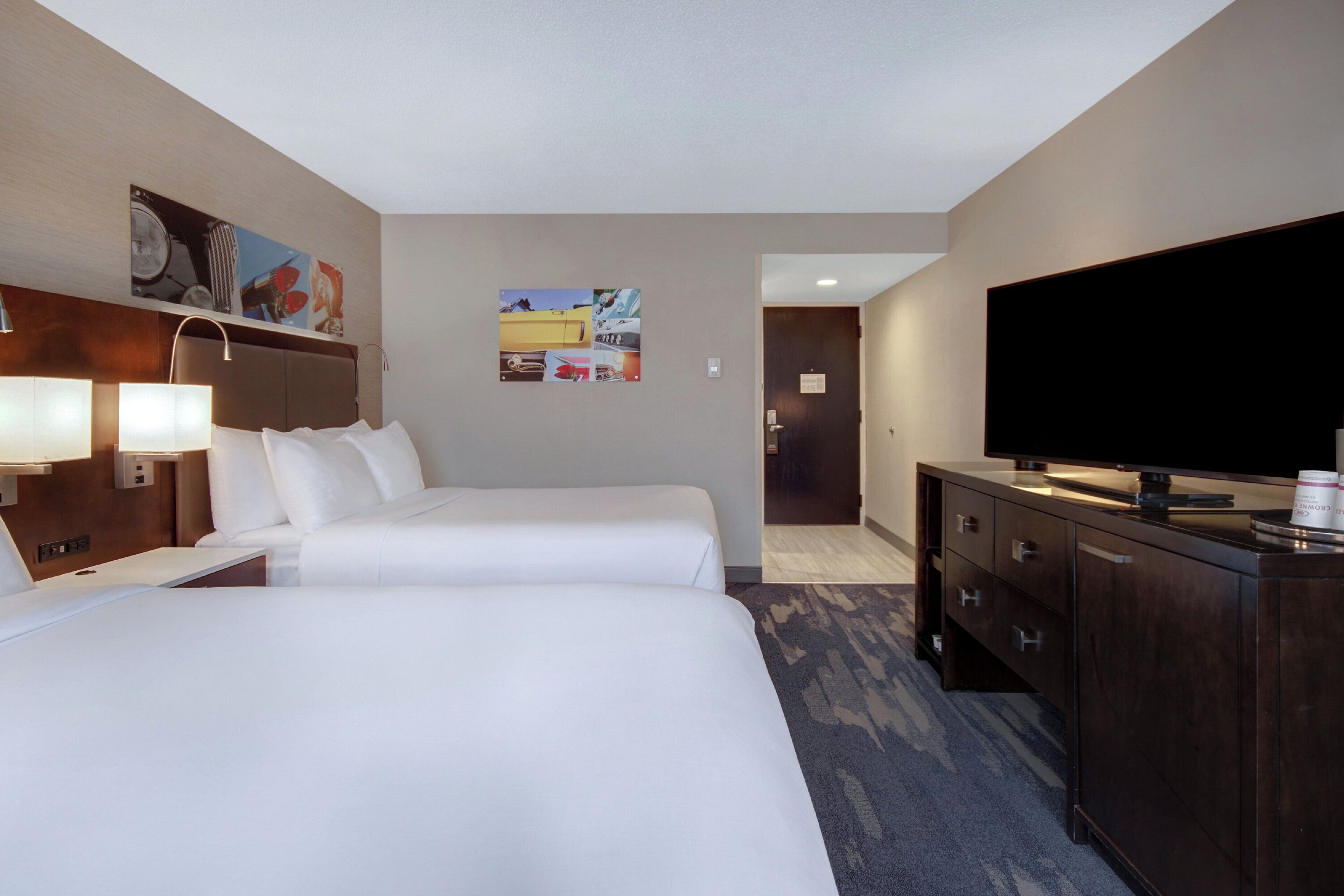 Habitación de hotel con dos camas, televisión, escritorio y cómoda.