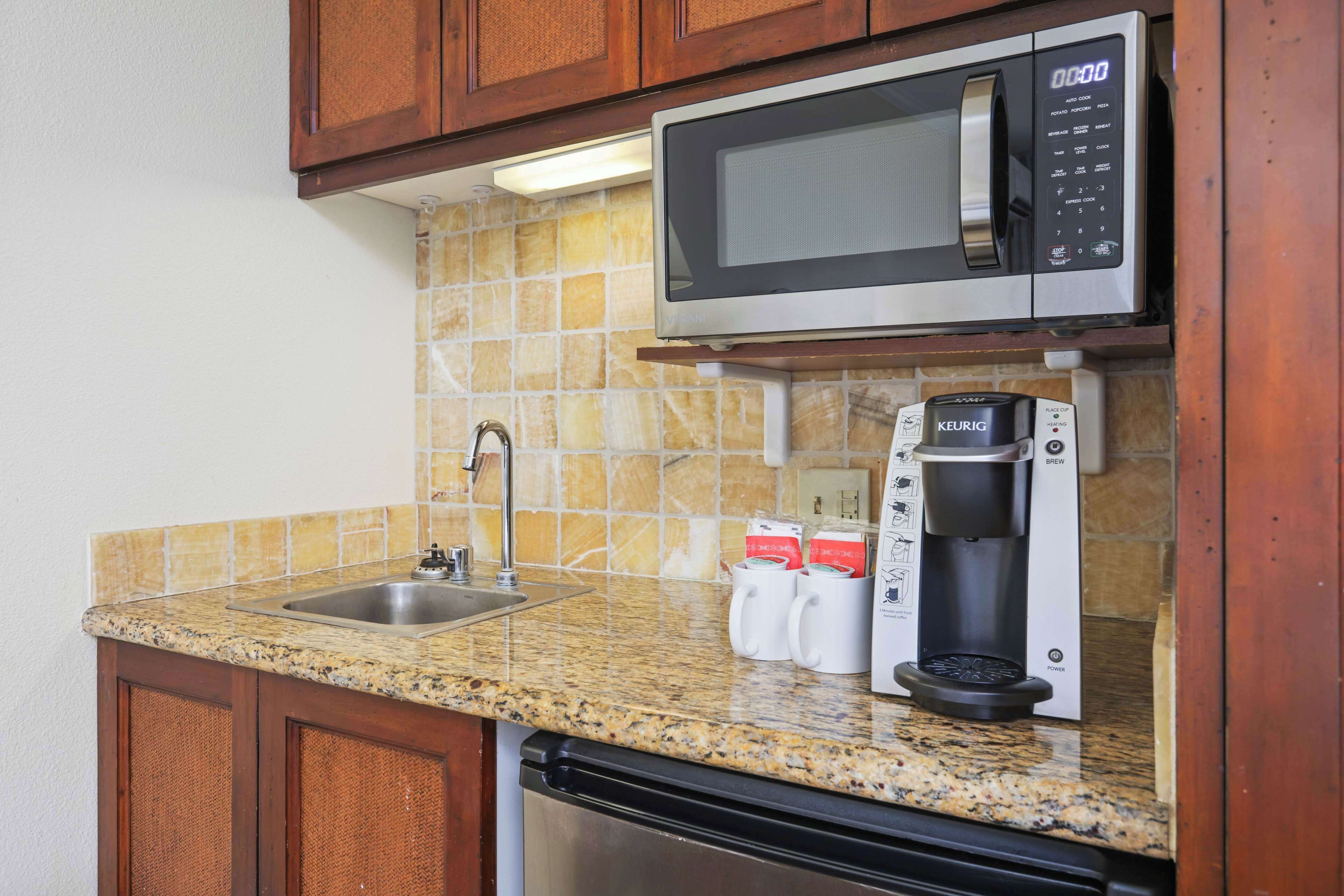 Una cuina amb microones d'acer inoxidable, una cafetera Keurig i un rentaplat.