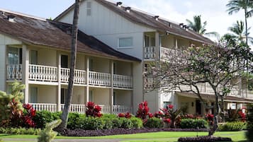 A multi-story hotel with balconies, surrounded by well-maintained gardens and palm trees.